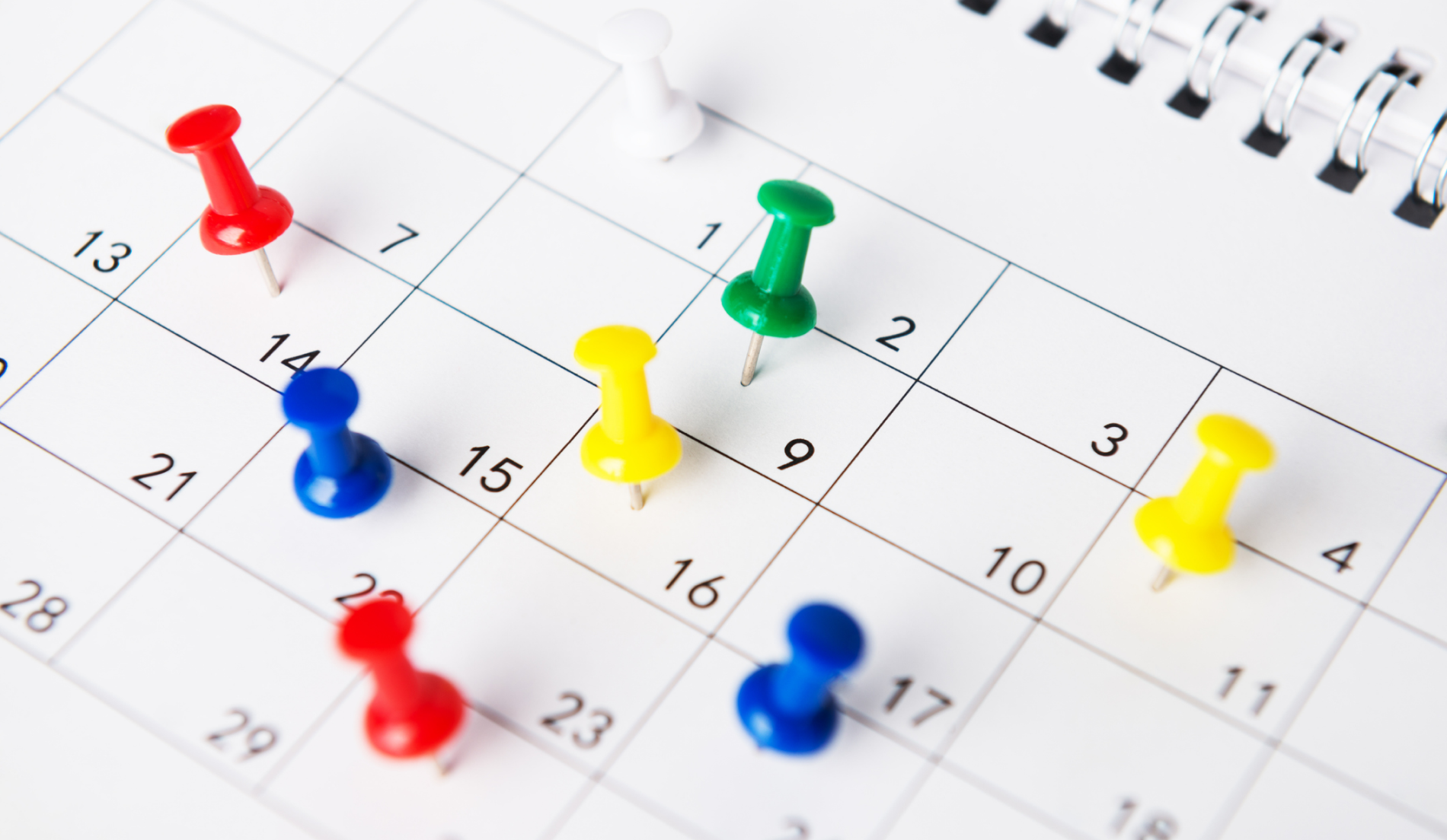 Calendar with colorful push pins.