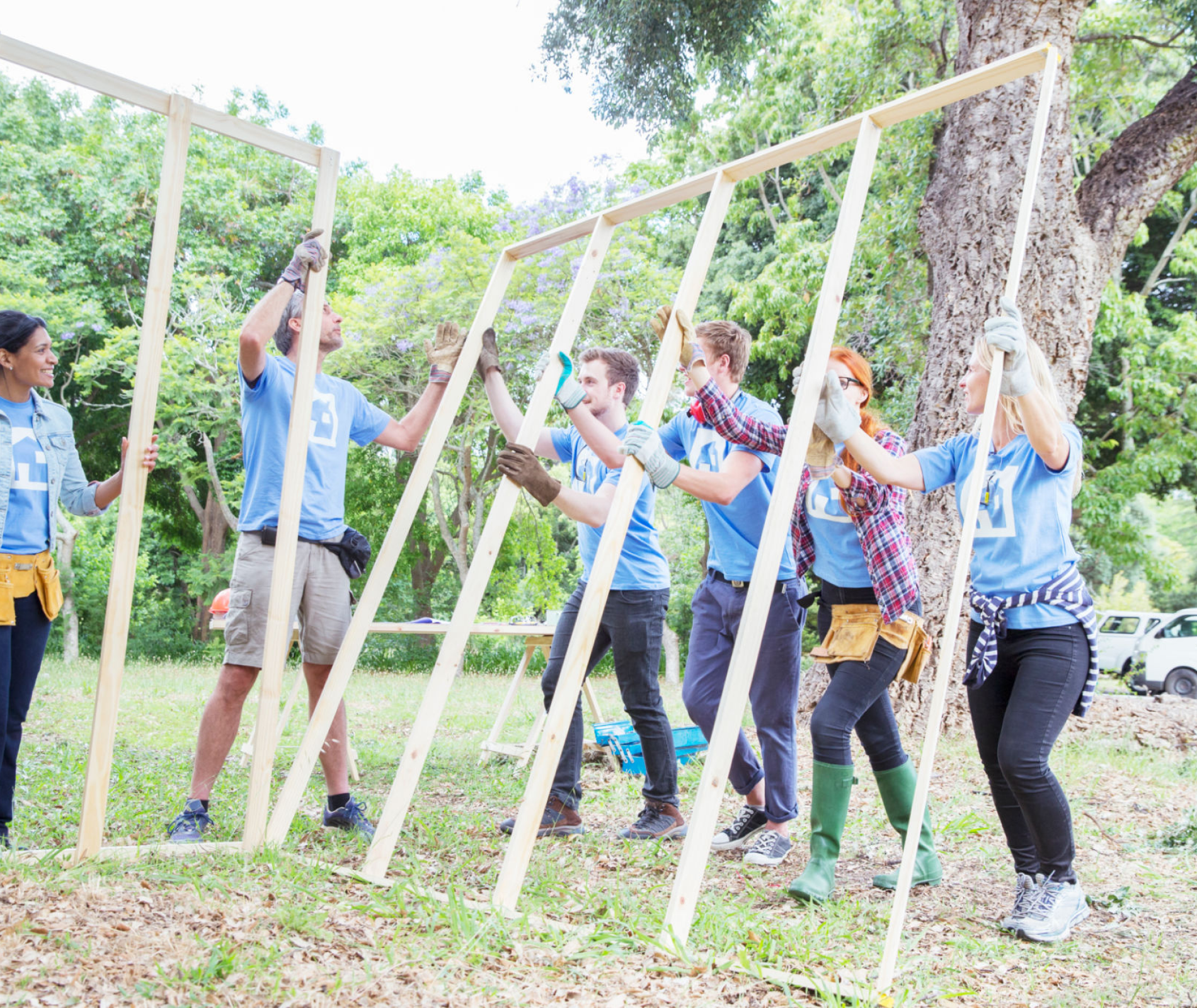 Volunteers building a wooden frame outdoors.