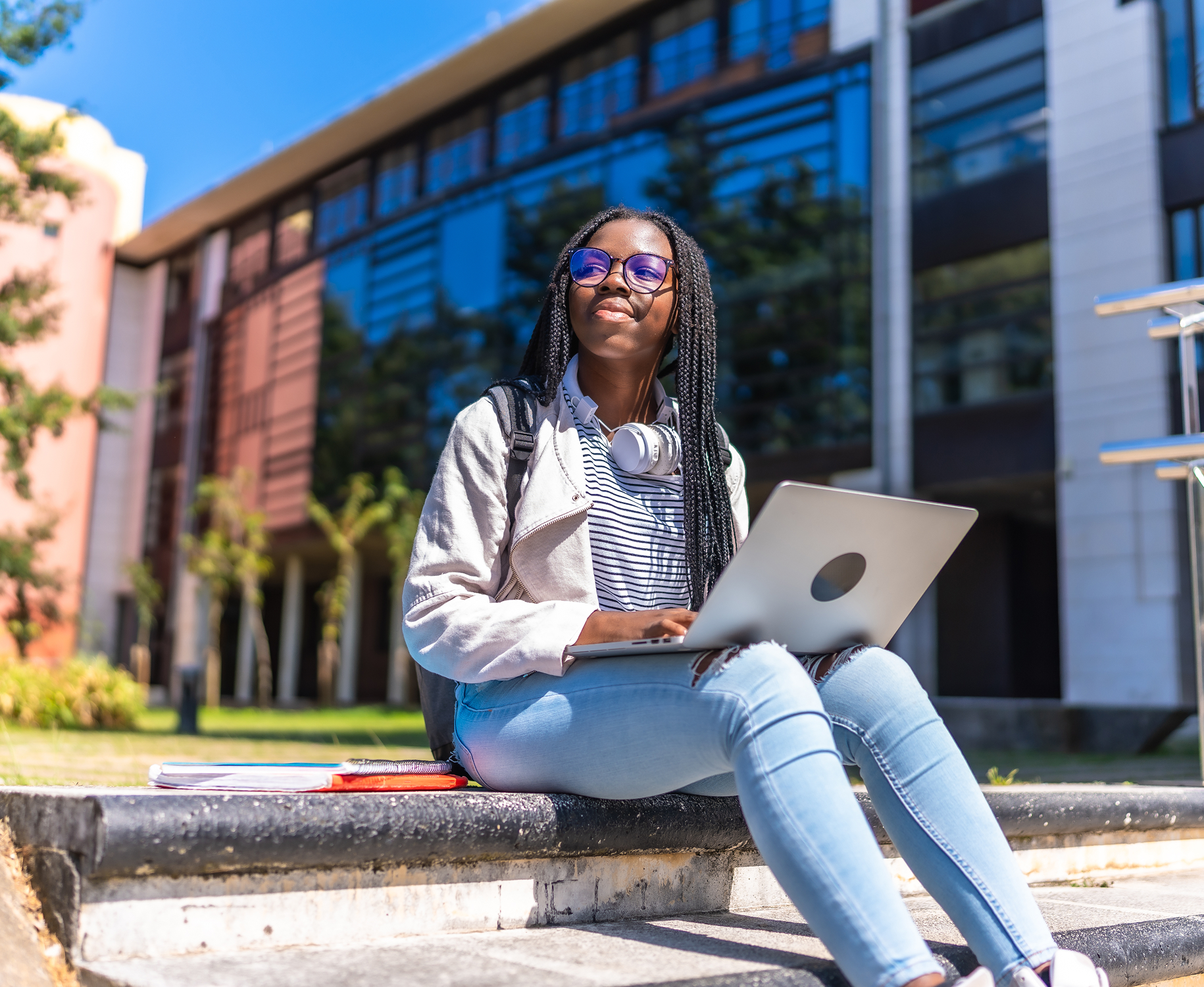 Young woman using laptop outdoors on a sunny day.