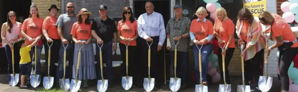 Four people holding shovels for a groundbreaking ceremony.