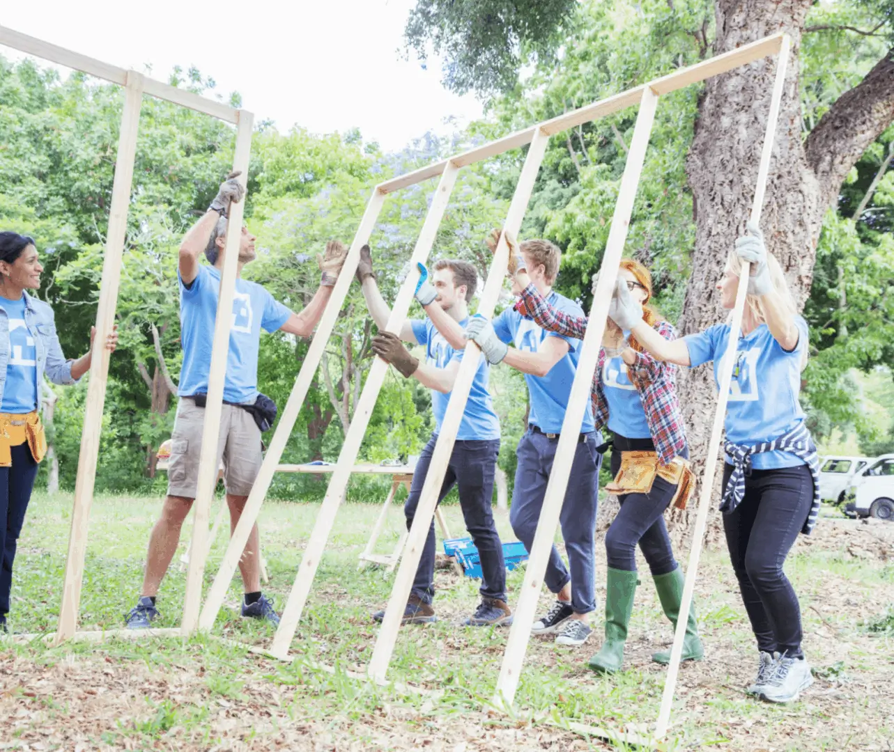 Volunteers building a wooden frame outdoors.