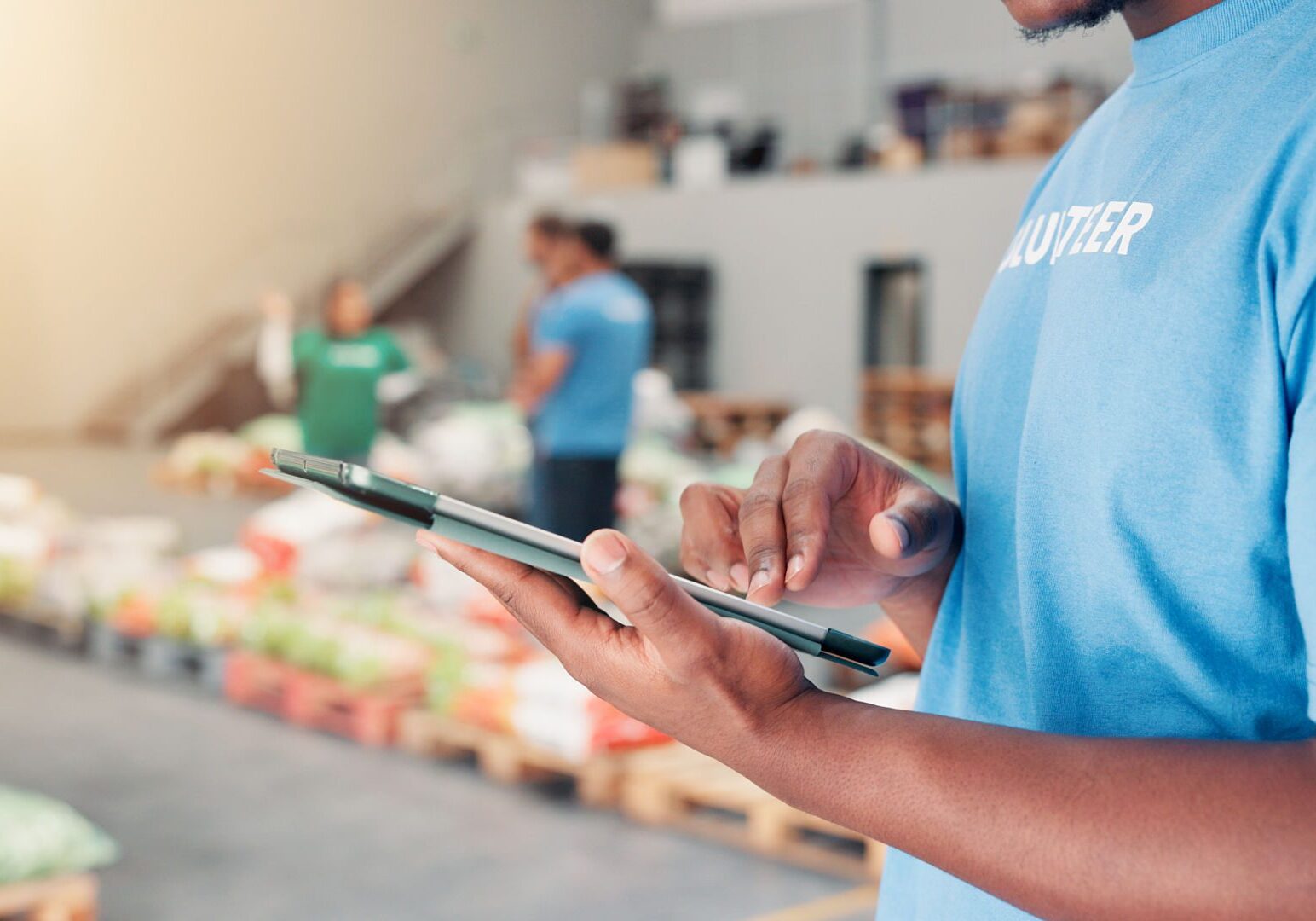 Volunteer using tablet in warehouse environment.